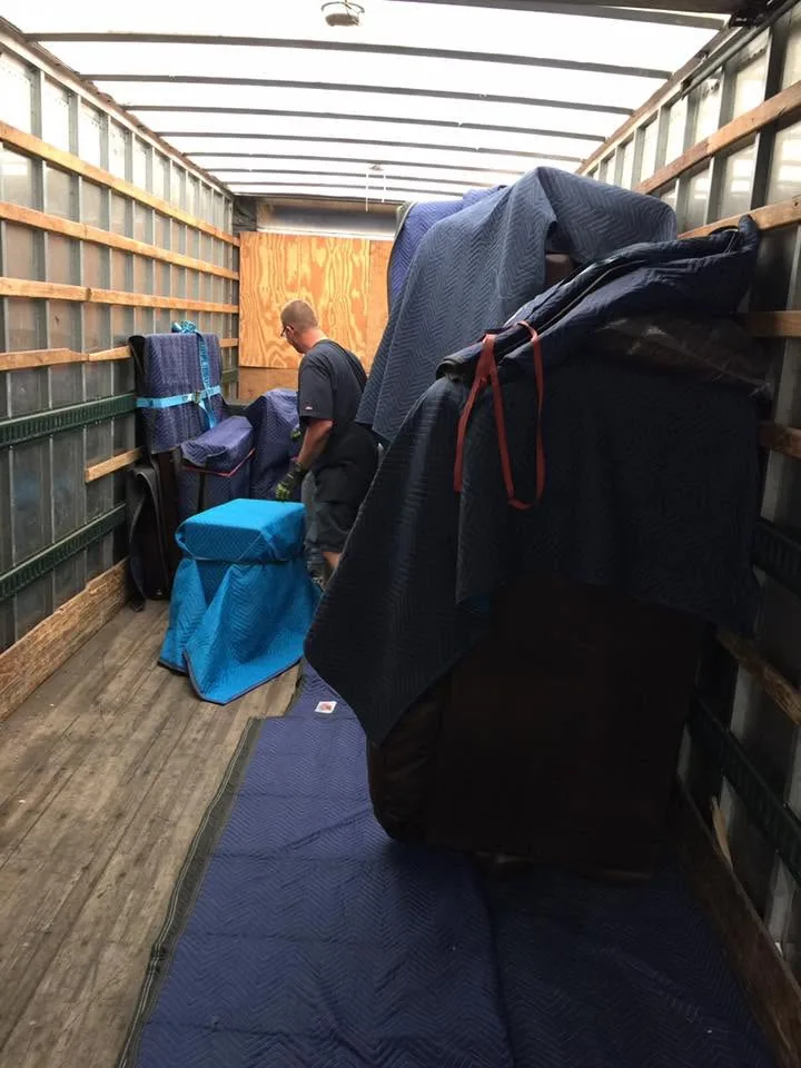 Mover loading padded furniture into a truck for moving and storage in Tennessee